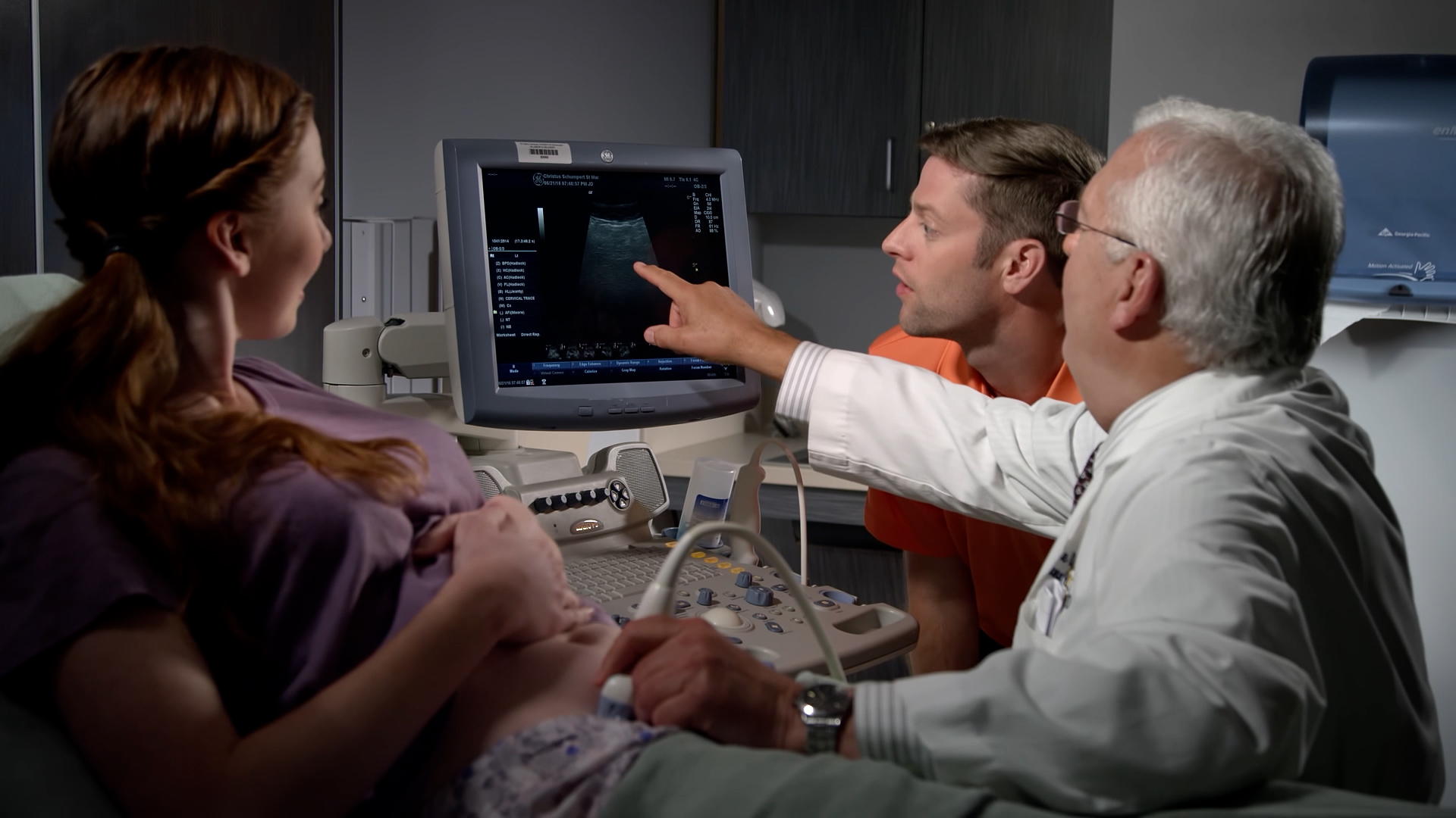 Expectant mother and her partner look on as a physician points to the monitor during a prenatal ultrasound appointment.