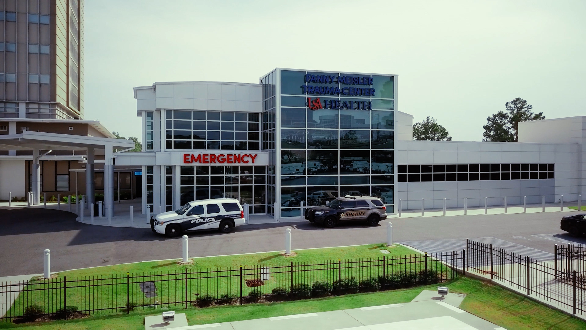Aerial view of the Fanny Meisler Trauma Center at USA Health, with police and sheriff vehicles parked at the emergency entrance.